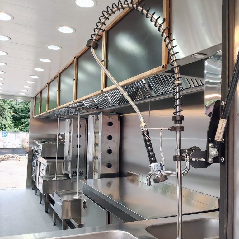 Innenraum eines Foodtrailers in Weiß mit Edelstahltechnik, Oberschränken, LED-Decke und Arbeitszeile – für Catering & Events